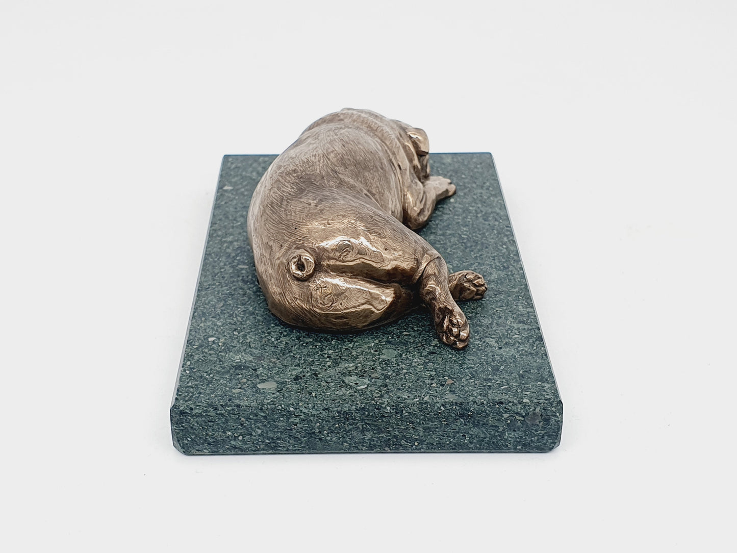 A sculpture of an English Bulldog sleeping on a Lakeland slate base