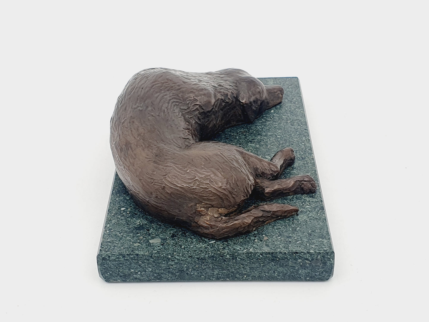 A bronze sculpture of a Golden Retriever sleeping on a Lakeland Slate base