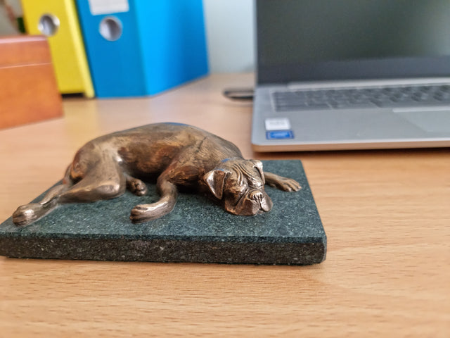 A bronze sculpture of a Boxer dog sleeping.