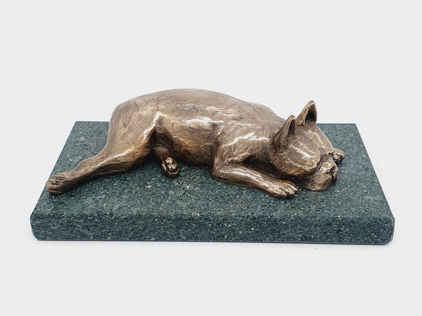 A sculpture of a sleeping Boston Terrier in bronze on a Lakeland slate base