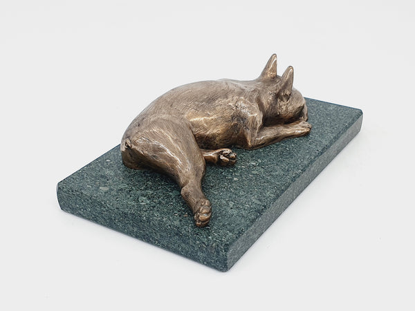 A sculpture of a sleeping Boston Terrier in bronze on a Lakeland slate base