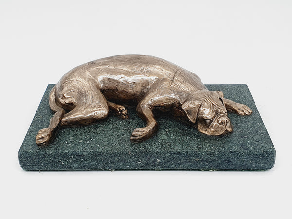 A sculpture of a sleeping Boxer Dog in bronze on a Lakeland slate base