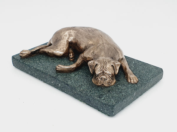 A sculpture of a sleeping Boxer Dog in bronze on a Lakeland slate base