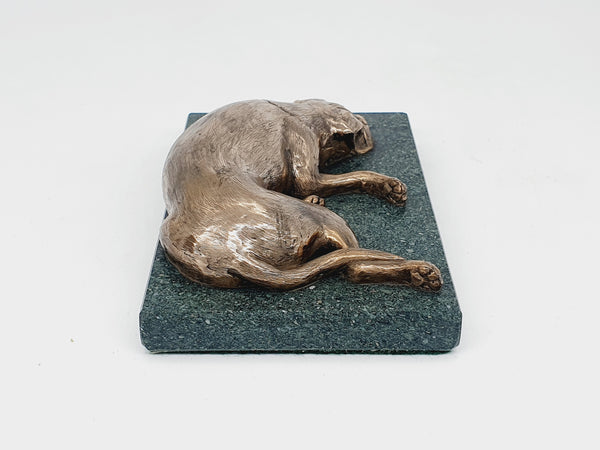 A sculpture of a sleeping Boxer Dog in bronze on a Lakeland slate base