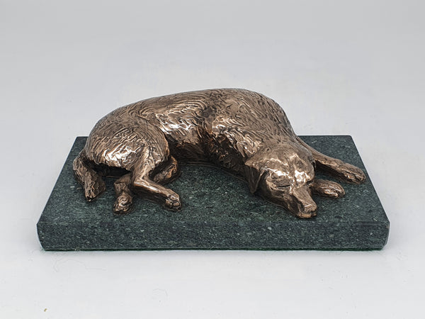 A bronze sculpture of a Golden Retriever sleeping  on a Lakeland Slate base