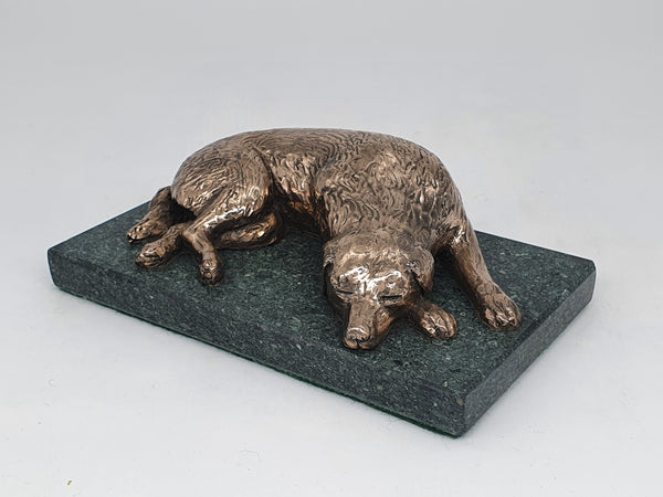 A bronze sculpture of a Golden Retriever sleeping  on a Lakeland Slate base