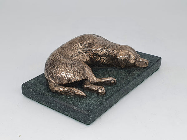 A bronze sculpture of a Golden Retriever sleeping  on a Lakeland Slate base