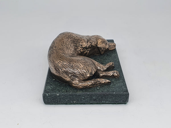 A bronze sculpture of a Golden Retriever sleeping  on a Lakeland Slate base