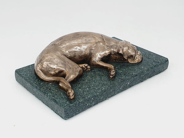 A sculpture of a sleeping Boxer Dog in bronze on a Lakeland slate base