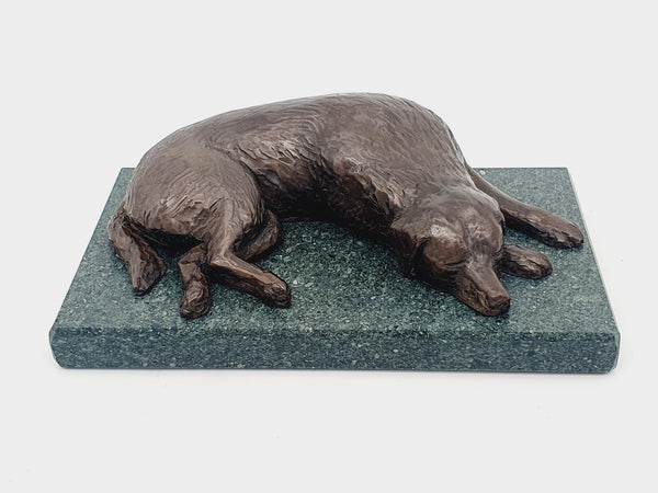 A bronze sculpture of a Golden Retriever sleeping  on a Lakeland Slate base