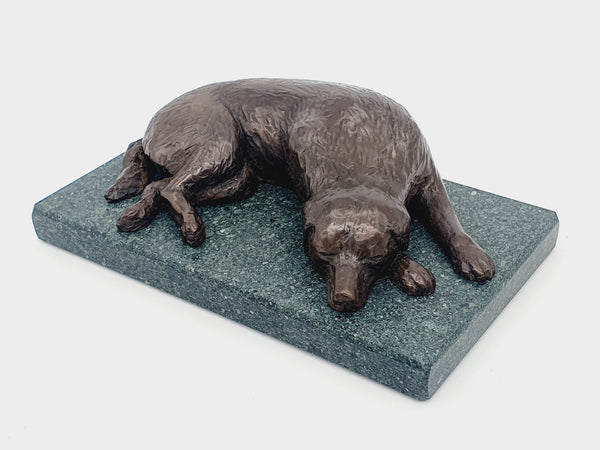 A bronze sculpture of a Golden Retriever sleeping  on a Lakeland Slate base