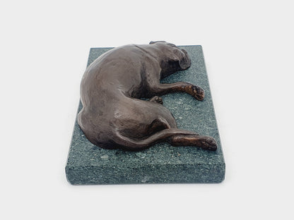 A sculpture of a sleeping Boxer Dog in bronze on a Lakeland slate base