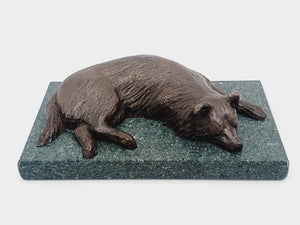 A bronze sculpture of a sleeping Border Collie on a Lakeland slate base