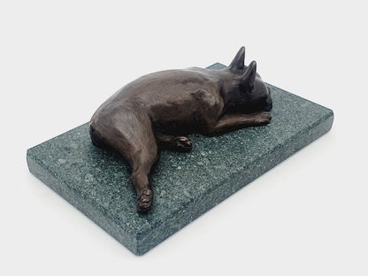 A sculpture of a sleeping Boston Terrier in bronze on a Lakeland slate base