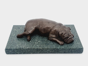 A sculpture of an English Bulldog sleeping on a Lakeland slate base