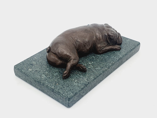 A sculpture of an English Bulldog sleeping on a Lakeland slate base