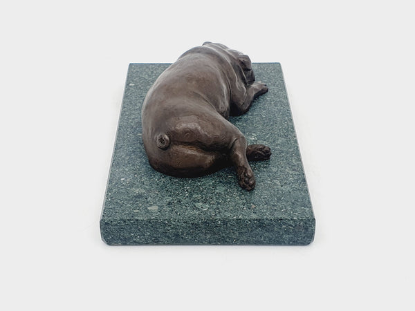 A sculpture of an English Bulldog sleeping on a Lakeland slate base