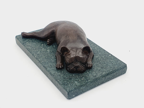 A sculpture of a French Bulldog sleeping on a Lakeland sate base